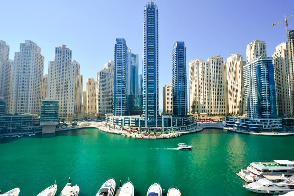 InterContinental Dubai Marina waterfront hotel with modern high-rise towers overlooking turquoise marina waters and moored boats, Dubai UAE