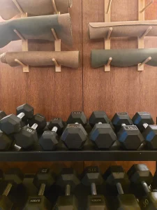 room2 Chiswick fitness room weights area with a rack of dumbbells and rolled exercise mats stored on wall pegs