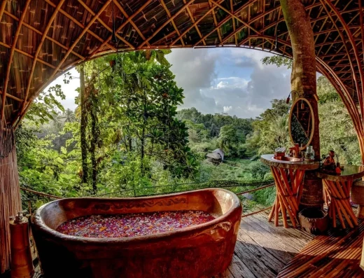 A flower-filled soaking tub in a bamboo pavilion overlooking lush rice fields and jungle at Bambu Indah.