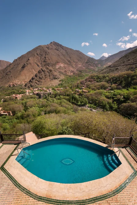 Pool overlooking Atlas Mountains valley with Berber villages, terraced agriculture, and dramatic mountain peaks at Kasbah du Toubkal