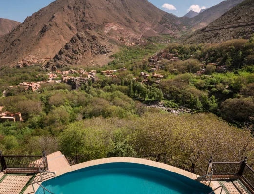 Pool overlooking Atlas Mountains valley with Berber villages, terraced agriculture, and dramatic mountain peaks at Kasbah du Toubkal