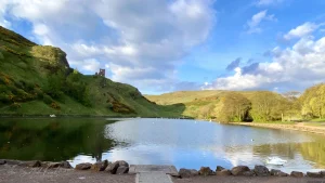 Peaceful lake with hills and castle ruins in Edinburgh