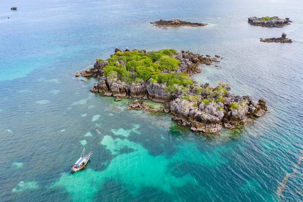Aerial view of Korongo snorkeling spot with turquoise waters, rocky islands with lush vegetation, and traditional fishing boats near Chole Mjini