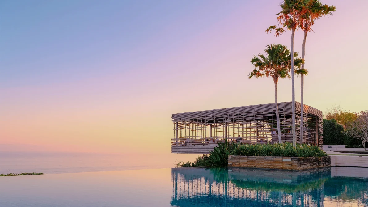 Modern sunset cabana with slatted wooden design overlooking an infinity pool and ocean at dusk at Alila Villas Uluwatu
