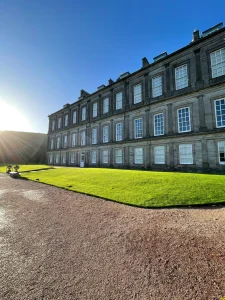 Historic stone mansion with green lawn and blue sky in Edinburgh