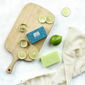 Jungle Culture lime exfoliating soap bar with sliced limes on a wooden board and white towel.