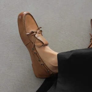 Brown leather Darsie block heels loafers with round toe, bow detail, and low block heel worn with black trousers.