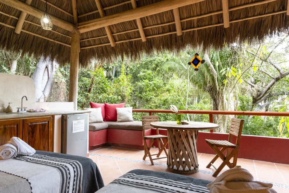 Open-air jungle suite with kitchenette and terrace seating at Tailwind Jungle Lodge