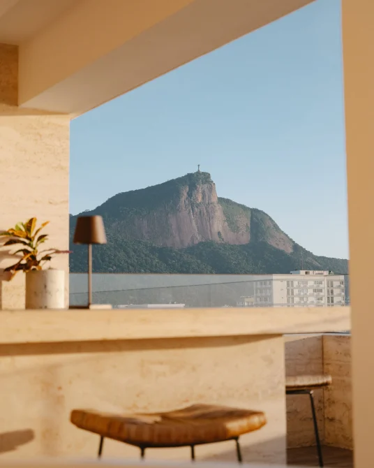 Terrace bar with stools overlooking a mountain topped by the Christ the Redeemer statue in Rio.