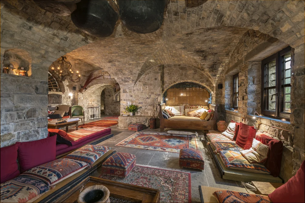 Rustic stone-vaulted lounge at Eremito Hotelito with low seating, colorful textiles, and warm ambient lighting.