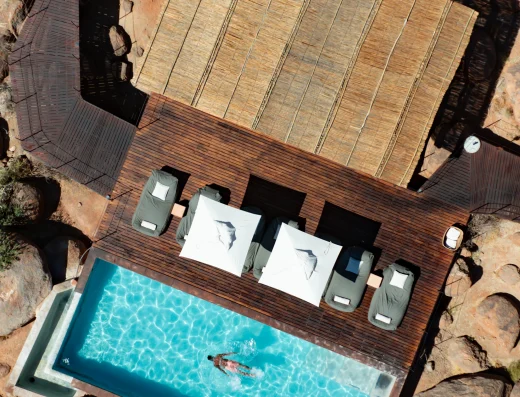 Aerial view of the pool and sun loungers on a wooden deck among granite boulders at Zannier Sonop, Namibia
