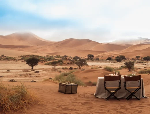 Private desert dining setup with two chairs and table in the Sossusvlei dunes near Zannier Sonop, Namibia